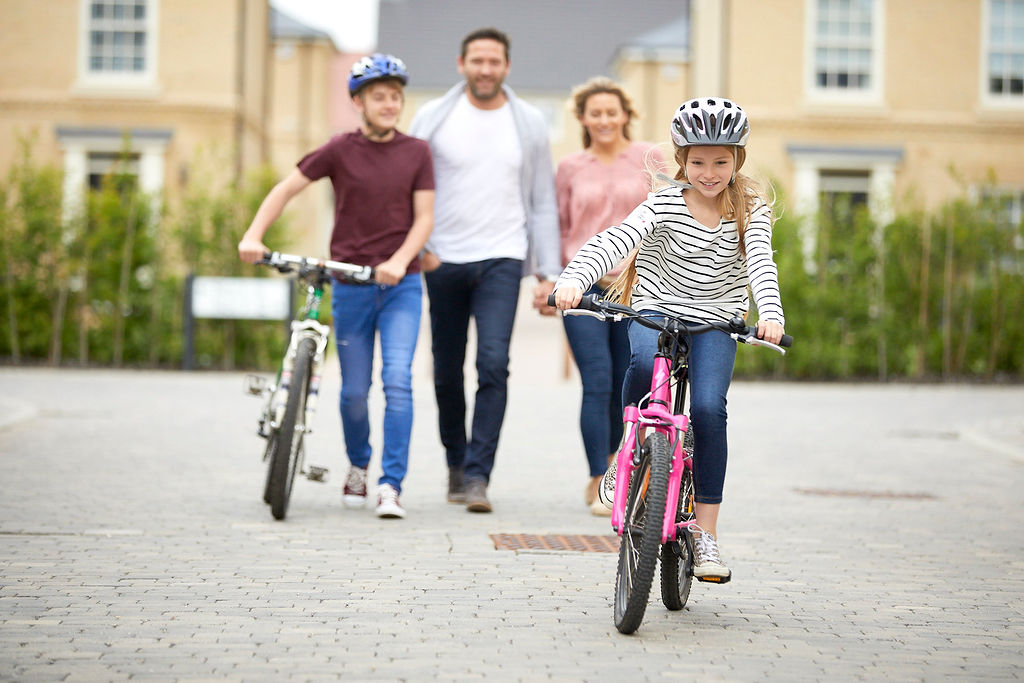 A family of four with children on their bikes in a Hopkins Homes' development