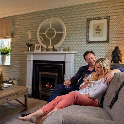A couple snuggled up on a sofa, enjoying a glass of wine