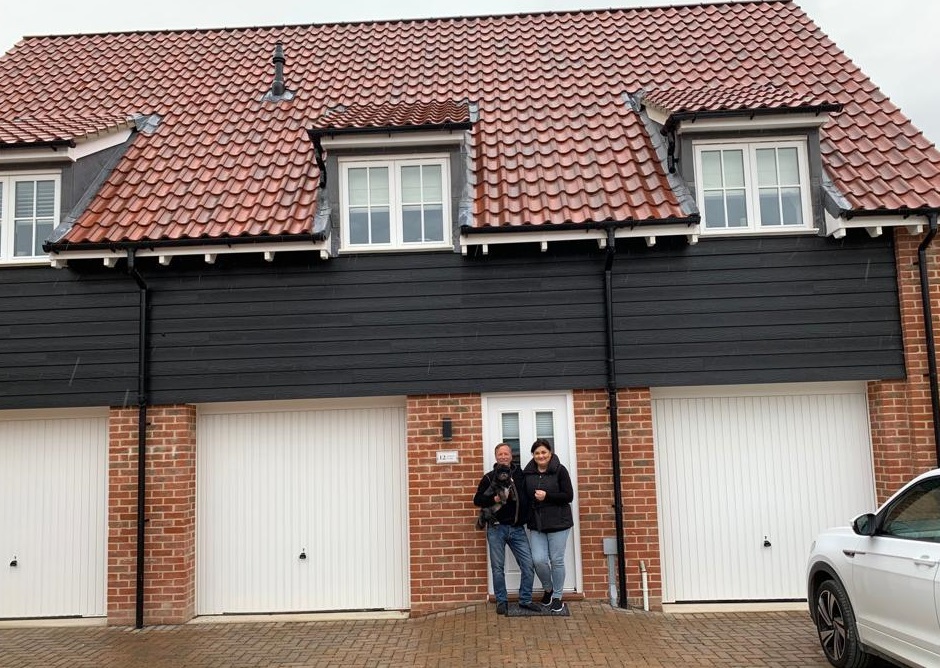 Man and woman in front of a house with a dog