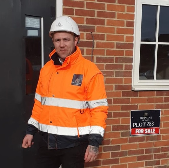 Man outside new built home wearing PPE