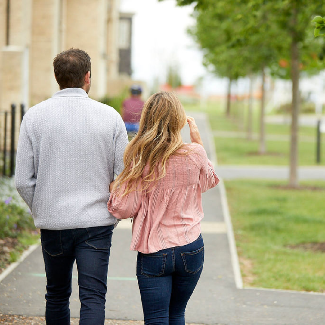 The backs of a man and a woman walking on a Hopkins Homes development