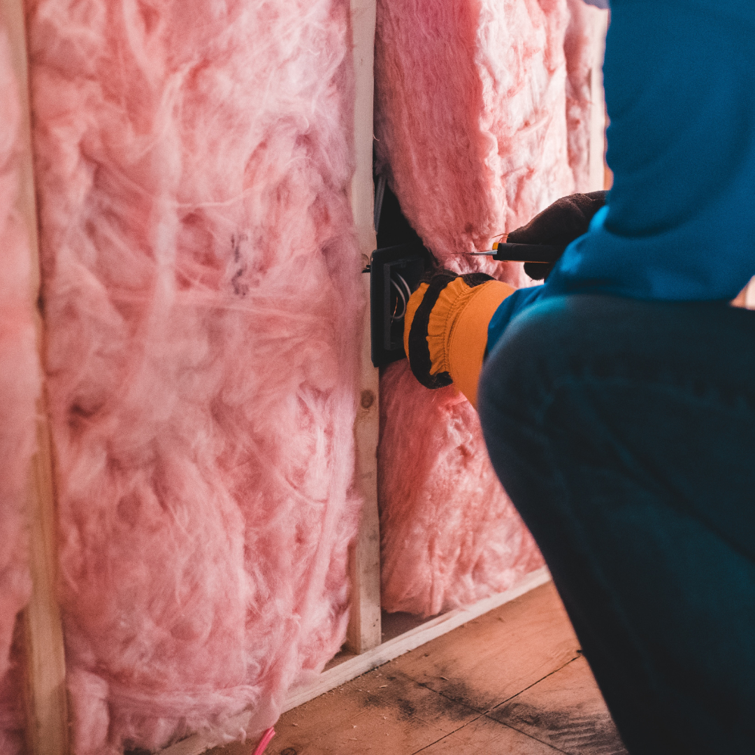 Person installing insulation in a wall