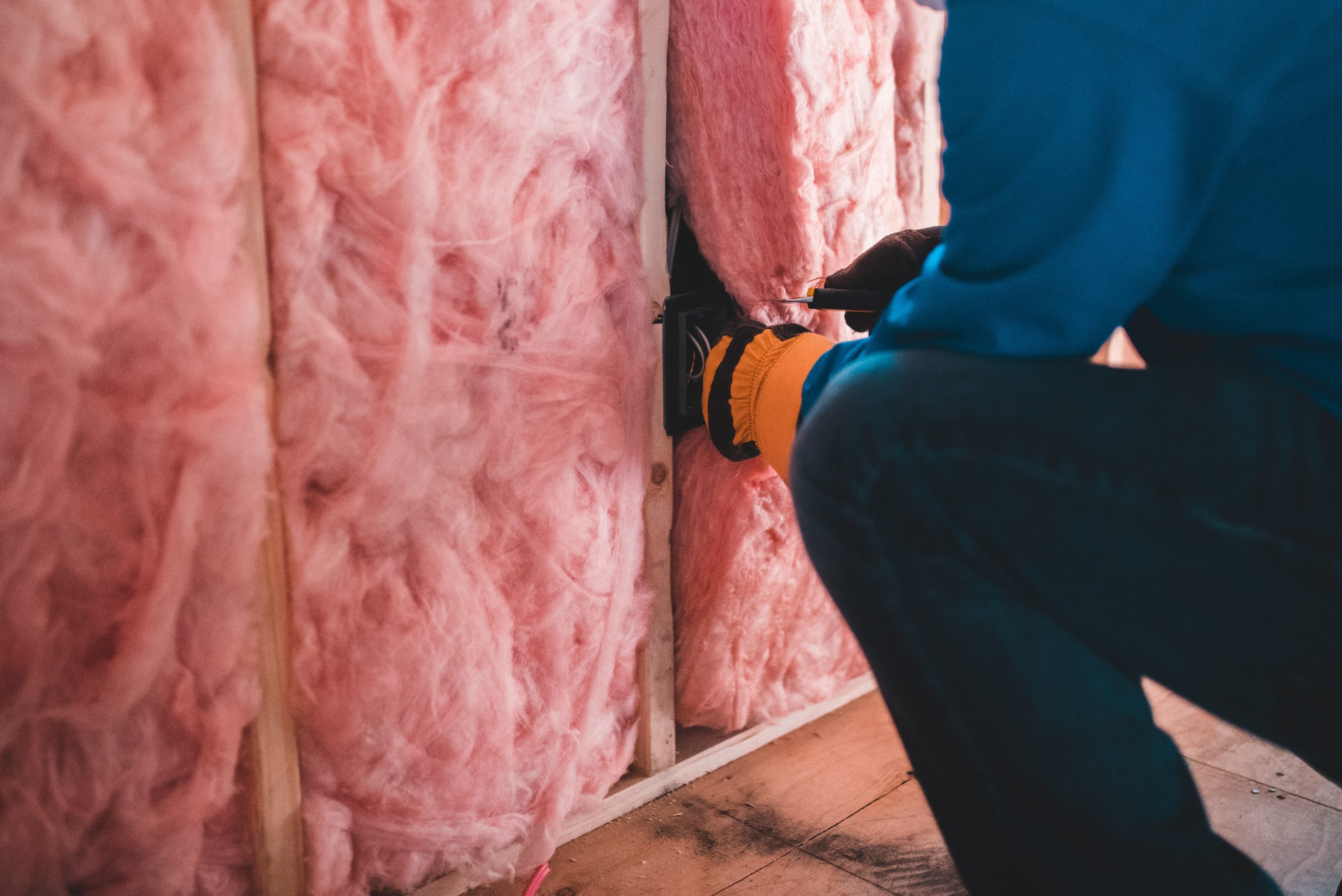 Person installing insulation in a wall