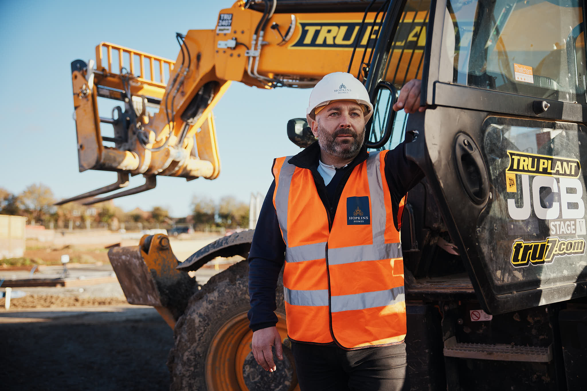 Man in hard hat and hi vis with digger